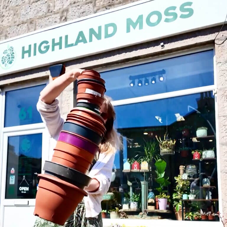 Shopfront of Highland Moss plant store with vibrant flower pots and diverse plant display.